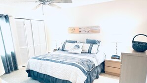 Ein Schlafzimmer mit einem Bett, Nachttischen, einer Lampe, einem Deckenventilator und einem Wandbild.