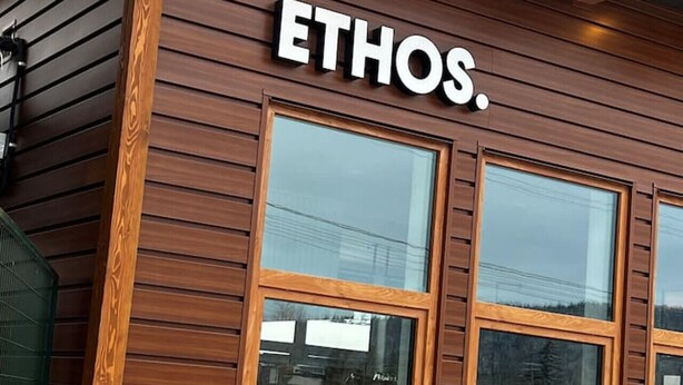 La façade d’un immeuble affiche en grand le nom « ETHOS » au-dessus de trois grandes fenêtres.