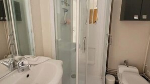 Ein modernes Badezimmer mit einer Duschkabine, einem weißen Waschbecken und einer Toilette.