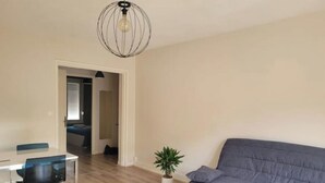 Ein modernes Wohnzimmer mit einer grauen Couch, einem Esstisch mit Stühlen und einer Topfpflanze.