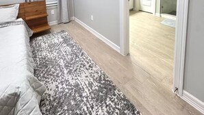 A bedroom with a bed, a patterned rug, a skylight, and a door leading to a bathroom. - Home Away From Home - RGV (Edinburg)