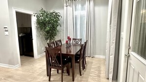 A dining area with a wooden table and chairs, a potted plant, and a ceiling light fixture. - Home Away From Home - RGV (Edinburg)