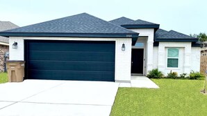 A modern two-story house with a dark blue garage door, a brick exterior, and a well-maintained lawn. - Home Away From Home - RGV (Edinburg)
