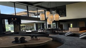 Een modern interieur met een grote, gebogen bank, een ronde houten salontafel en hanglampen.
