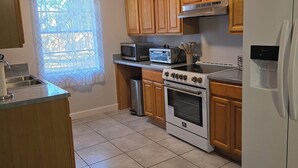 A kitchen with wooden cabinets, a stainless steel sink, a microwave, an oven, and a refrigerator. - Clean, Spacious, 3BR 1.5BA, Near Shipyards, Chevron, Beach, Casinos, Fenced yard (Pascagoula)