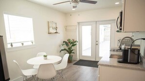 A compact kitchen with a dining area, a ceiling fan, and a potted plant. - Cornerstone House (St. Augustine)