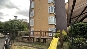 A playground with a yellow slide, a wooden climbing structure, and a bike parked nearby. - Departamento Bellavista (Osorno)