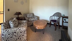 A living room with a sectional sofa, a round coffee table, and a wicker chair. - Departamento Bellavista (Osorno)