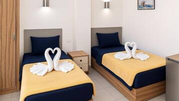 Two double beds with matching blue headboards and yellow bedspreads, each adorned with white swan-shaped towels.