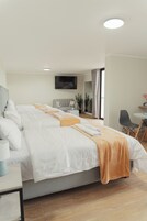 Una habitación de hotel con una cama grande, un escritorio, una silla, un televisor y una ventana con cortinas.