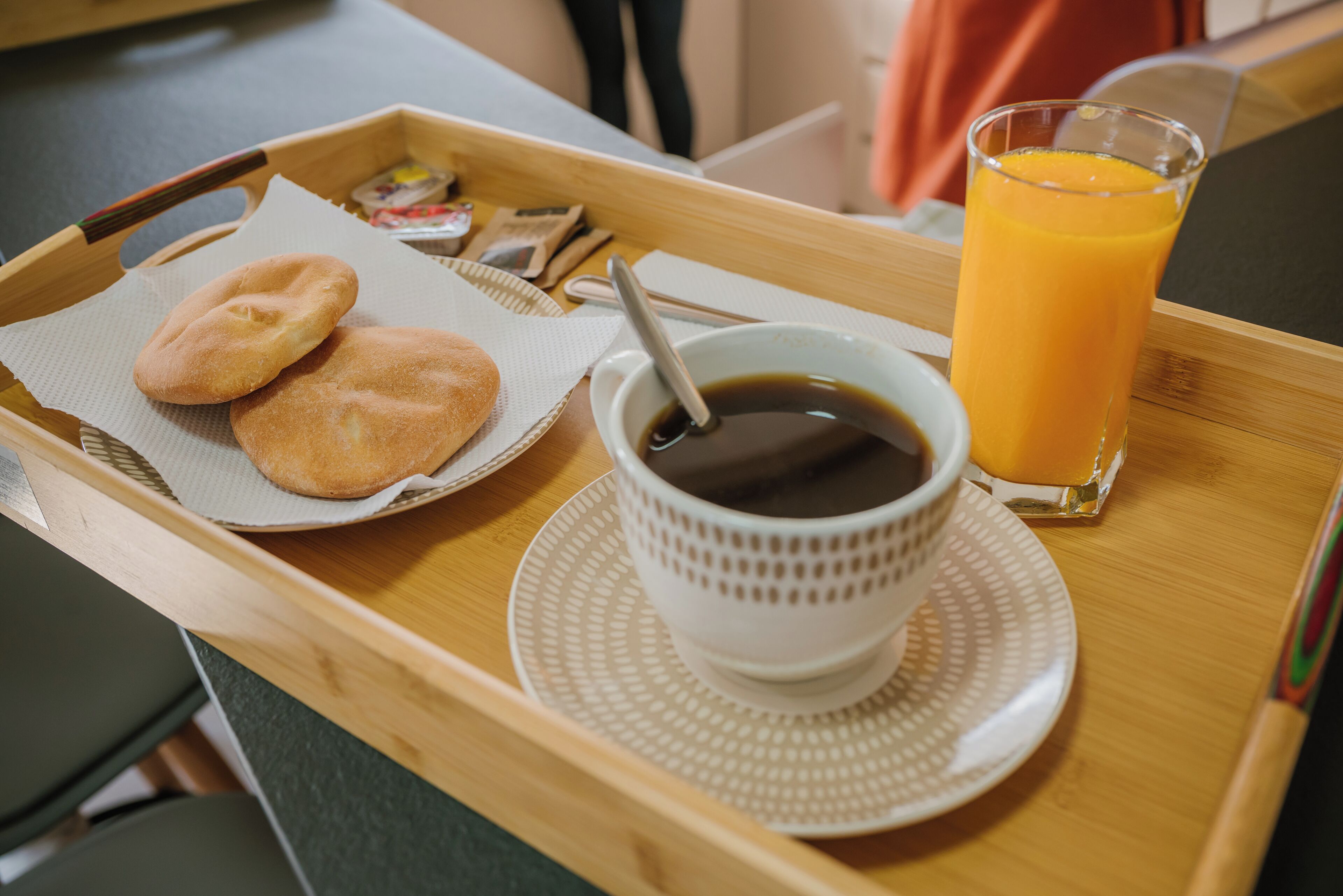 A tray with two cookies, a cup of coffee, and a glass of orange juice.