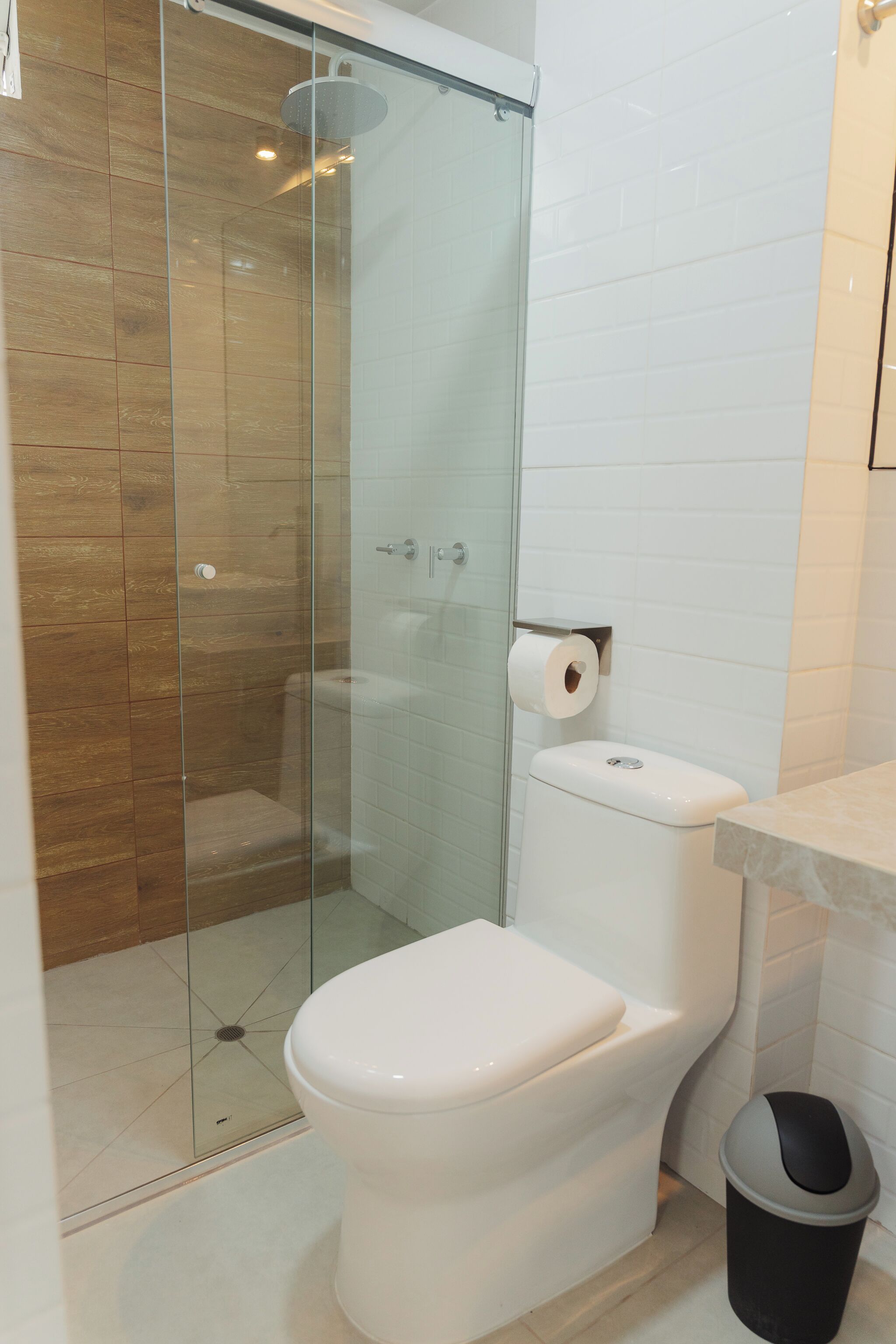 A bathroom with a glass-enclosed shower, a white toilet, and a marble countertop.
