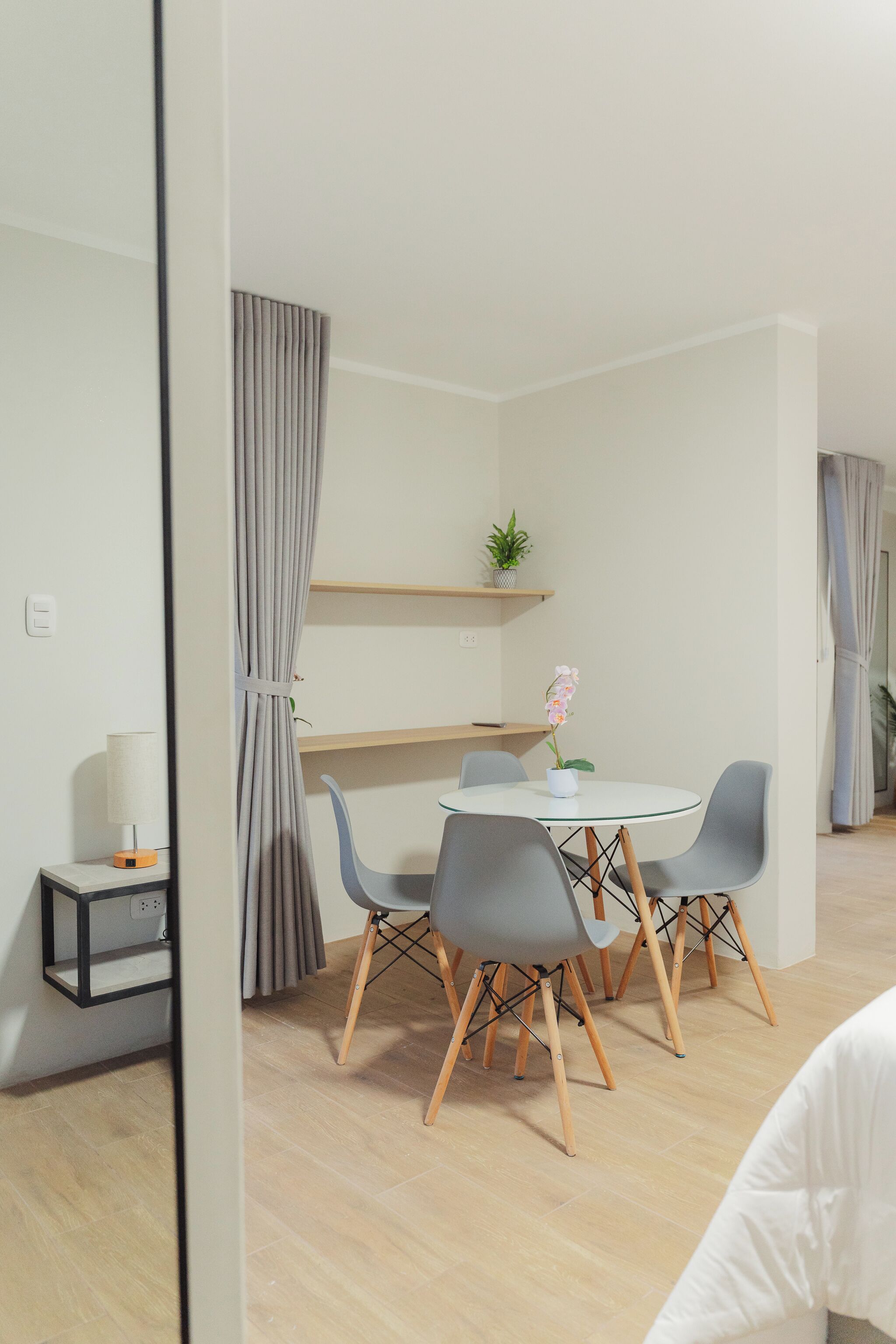 Un espace repas moderne avec une table ronde, des chaises grises et une orchidée en pot.