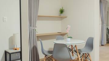 Un espace repas moderne avec une table ronde, des chaises grises et une orchidée en pot.