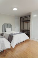 Un dormitorio con dos camas, un armario y una lámpara en el techo.