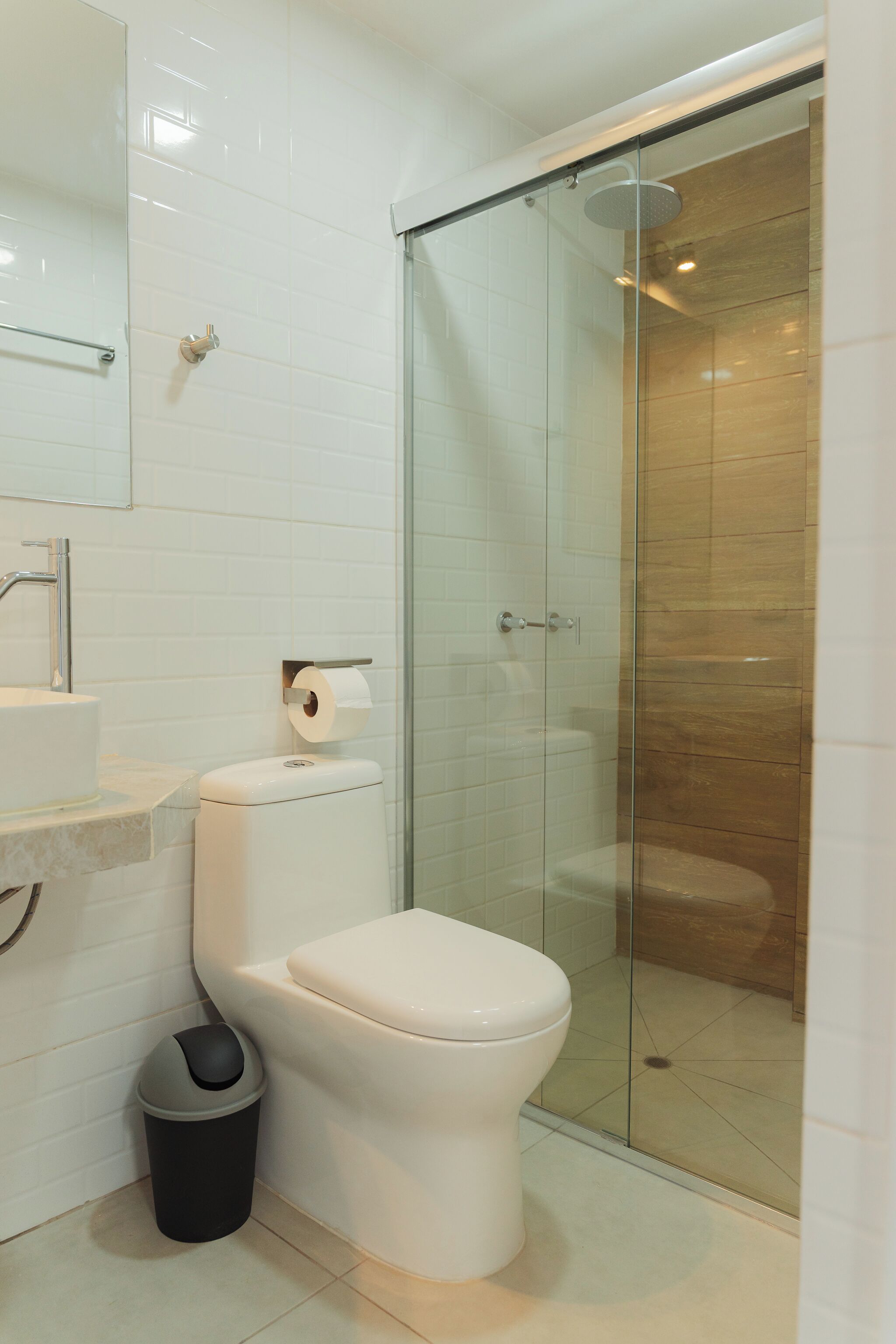 Une salle de bain moderne équipée de toilettes, d’un lavabo et d’une douche à parois de verre.