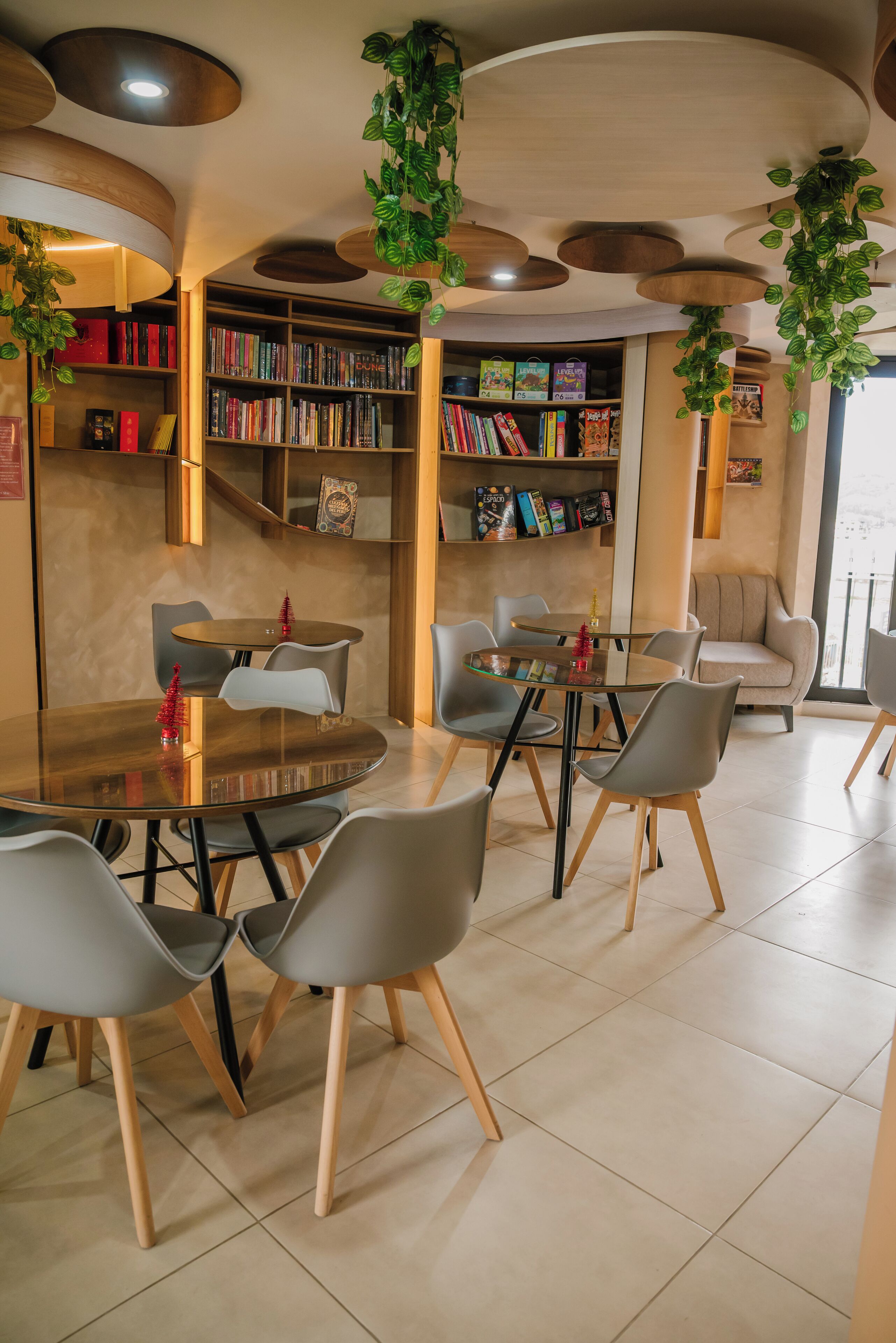 A modern library with round tables, grey chairs, and bookshelves filled with books.