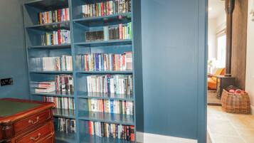 A room with a large blue bookshelf filled with books, a wooden dresser, and a wicker basket.