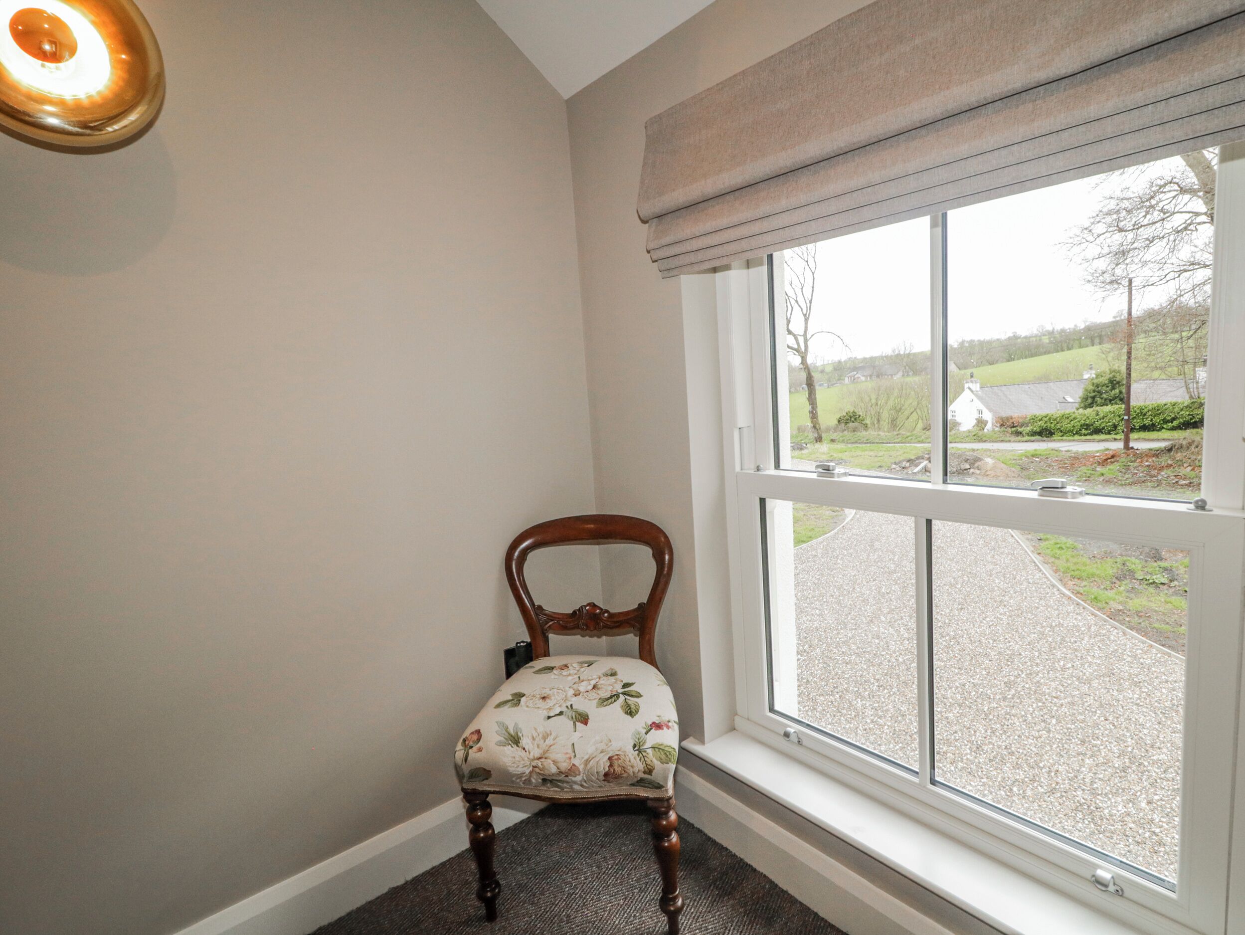 A corner room with a window, a chair, and a light fixture.