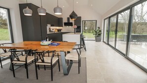 Uma sala de jantar moderna com mesa de madeira, cadeiras pretas e iluminação pendente.