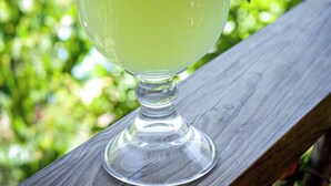 Un verre à cocktail orné d’une tranche de citron vert, posé sur une terrasse en bois.