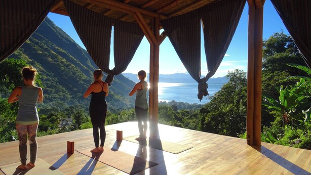 Une terrasse en bois offrant une vue sur un paysage montagneux et un plan d’eau.