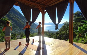 Una terraza de madera con vista a un paisaje montañoso y un cuerpo de agua.