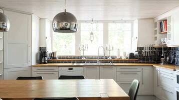 A modern kitchen with a wooden table, white cabinets, and a large window.