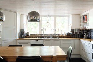 Een moderne keuken met een houten tafel, witte kastjes en een groot raam.