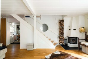A modern interior with a wooden staircase, a fireplace, and a dining area.