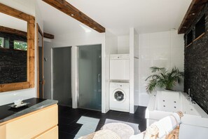 Een moderne badkamer met een grote spiegel, een wastafel, een wasmachine en een douche.