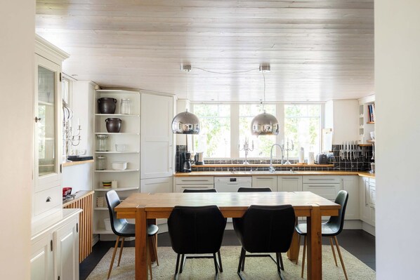 A modern kitchen with white cabinetry, a wooden dining table, and black chairs.