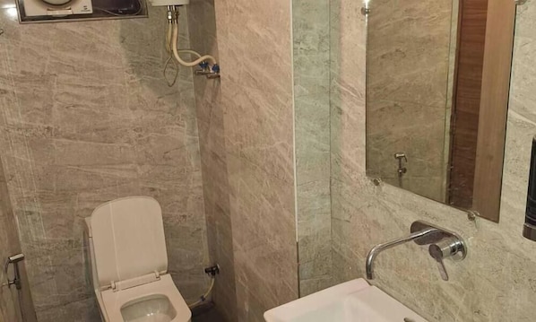 A bathroom with a toilet, sink, and mirror. - Hotel HR Residency (New Delhi)