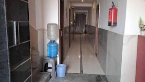 A hallway with a water dispenser, a fire extinguisher, and a small plant. - Hotel HR Residency (New Delhi)
