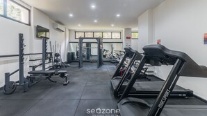 Une salle de sport équipée de tapis de course, de machines de musculation et d’un support pour les exercices de squat.