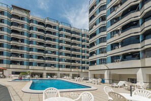 Un hôtel à plusieurs étages doté d’une piscine et d’un espace extérieur aménagé avec des sièges.