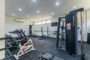 A gym with various exercise equipment, including treadmills, a stationary bike, and weightlifting machines. - Apt With Balcony Steps From Barra Beach Tlr0113 (Salvador)