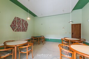 A room with a green and white color scheme, featuring a dining area with wooden tables and chairs, a decorative wall piece, and pendant lighting. - Apt With Balcony Steps From Barra Beach Tlr0113 (Salvador)