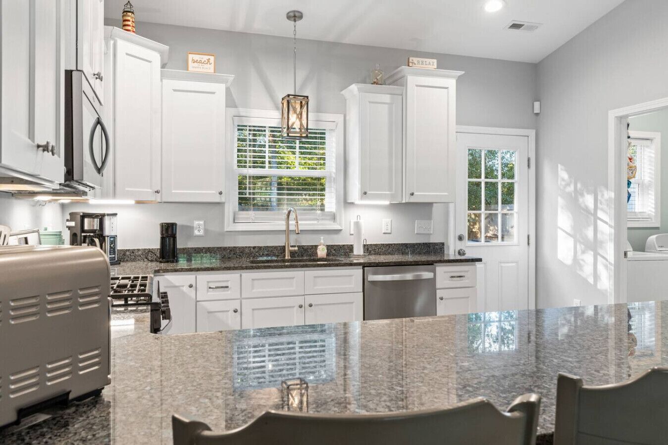 A modern kitchen with white cabinetry, a granite countertop, and a built-in dishwasher.