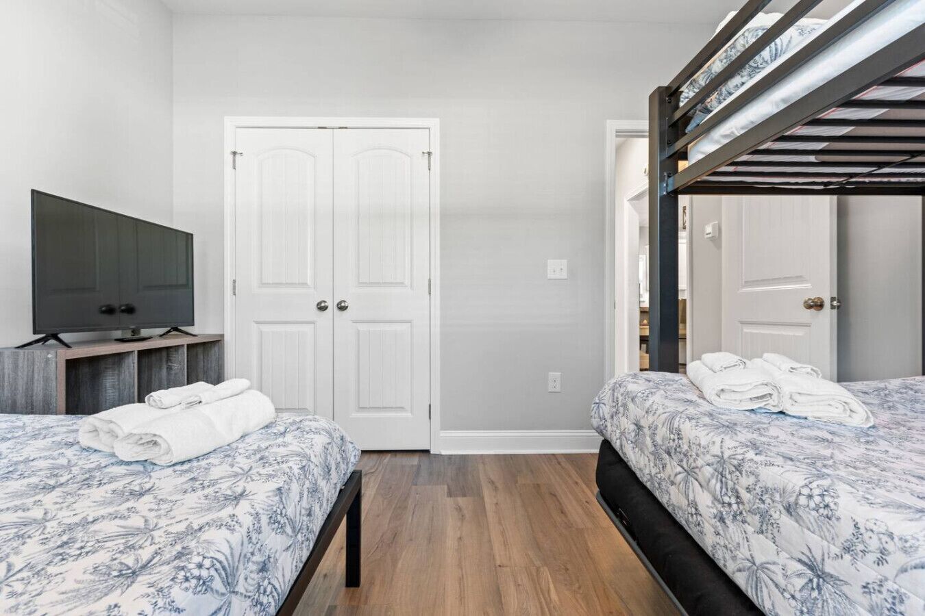 A hotel room with two beds, a TV, a wardrobe, and a bunk bed.