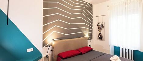 Una habitación de hotel moderna con una cama, un escritorio y una pared con un diseño en zigzag.