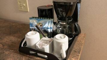 Eine Kaffeemaschine und zwei weiße Tassen auf einem Tablett.