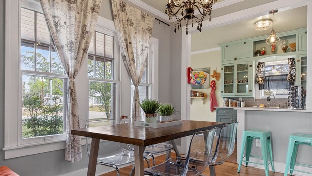 A dining area with a wooden table, clear chairs, and a kitchen with teal cabinets and a hanging light fixture. - New! Stunning Pet-Friendly Home + 3 Min to DT! (Seguin)