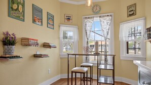 A kitchen with a wooden table, two stools, a hanging light fixture, and a window with a curtain. - New! Stunning Pet-Friendly Home + 3 Min to DT! (Seguin)