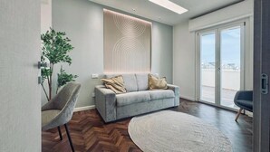 A modern living room with a grey sofa, a round rug, and a large window with a view. - Mameli View Cagliari (Cagliari)