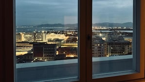 A view from a window overlooking a cityscape at dusk with buildings and a distant mountain range. - Mameli View Cagliari (Cagliari)
