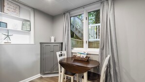 Ein Essbereich mit Tisch und Stühlen, einem Fenster mit Vorhängen, einem Schrank und Wanddekorationen.