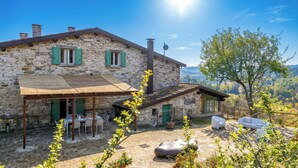 A stone house with a patio, outdoor seating, and a view of the countryside.