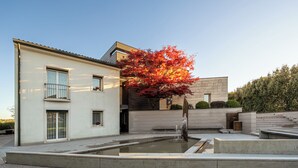 A modern building with a courtyard, a water feature, and a tree with autumn leaves. - Dimora delle Stelle 12, Emma Villas (Farra di Soligo)