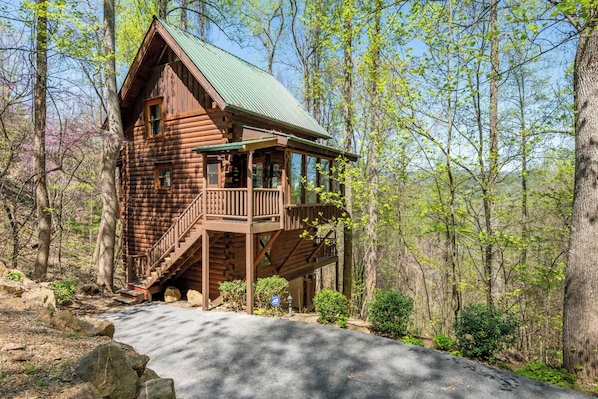 Une cabane en bois dotée d’un balcon, entourée d’arbres.